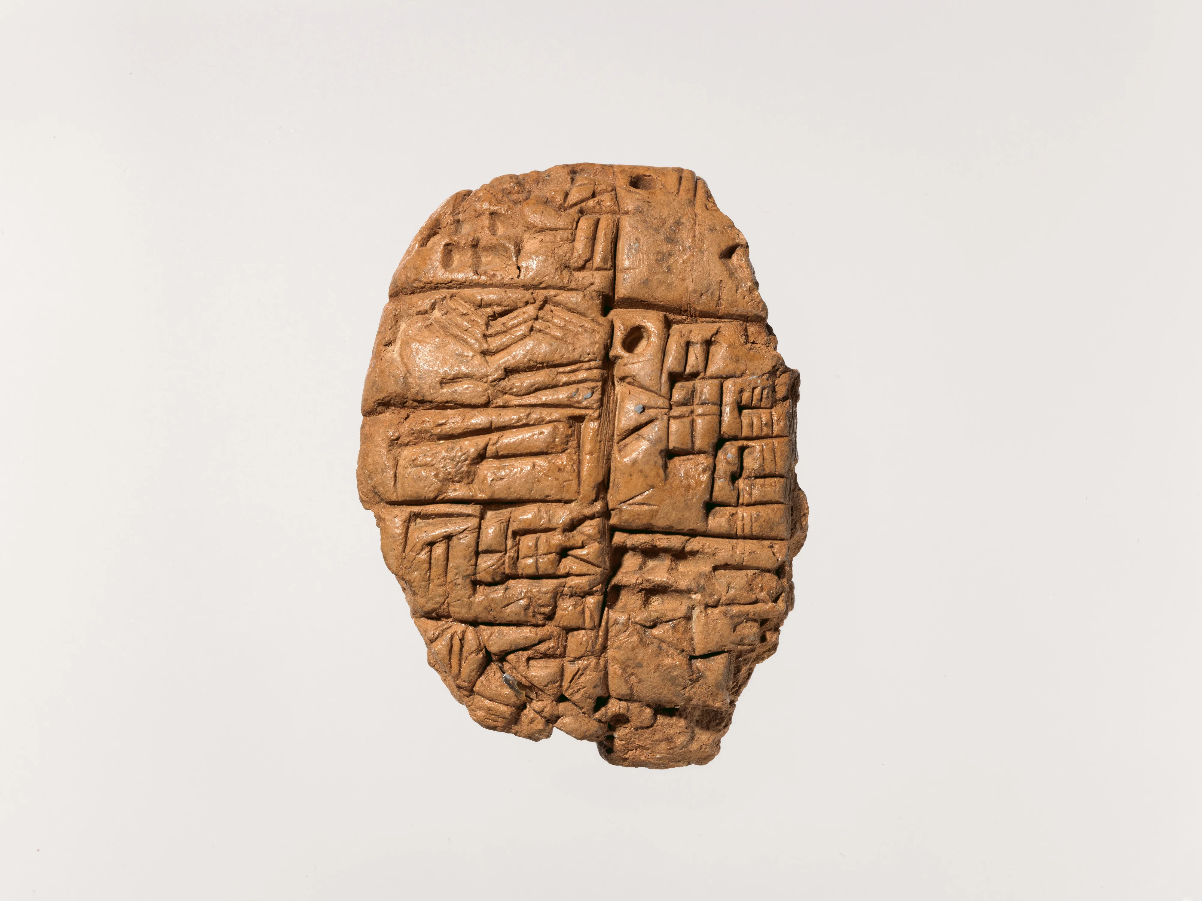 A clay cuneiform tablet, cracked and repaired, covered in dense rows of wedge-shaped administrative script.